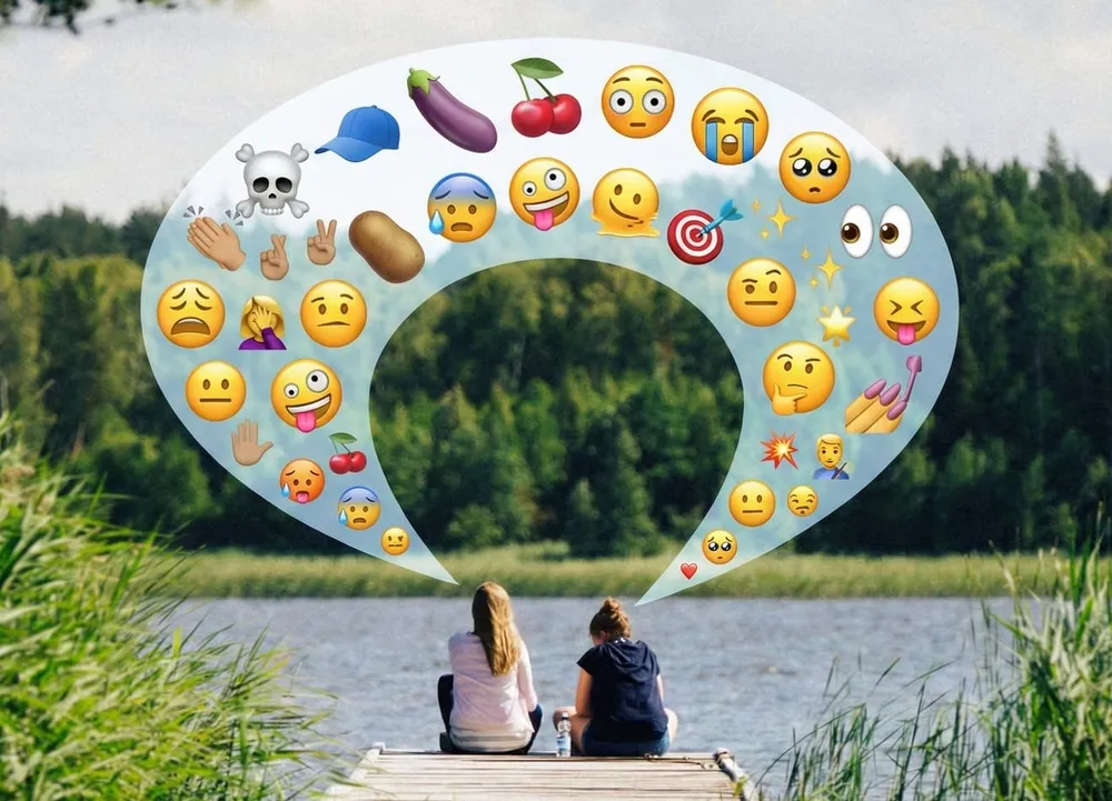 Zwei Frauen am See, über ihnen eine Sprechblase mit Emojis wie Totenkopf und Aubergine.